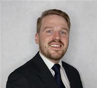 Head and shoulders of Jack Naylor in a dark suit and tie